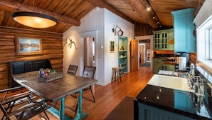 A rustic interior with a wooden dining table, a kitchen with a large island, and a cozy seating area.