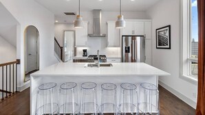 Uma cozinha moderna com ilha central, eletrodomésticos de aço inoxidável e iluminação pendente.