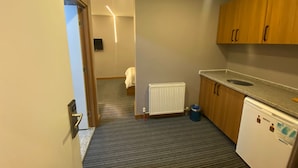 A compact hotel room with a kitchenette, a bed, a radiator, and a small trash bin. - Beşiktaş Vip İnn Hotel & Suites (Istanbul)