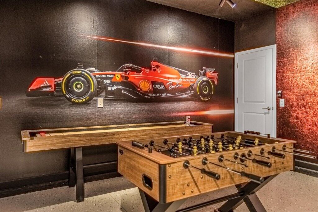 A foosball table and a racing car mural in a room with a door and textured wall.