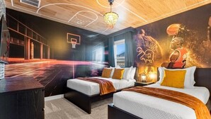 Habitación de hotel con un mural con temática de baloncesto, dos camas, un escritorio y un diseño de aro de baloncesto en la pared.