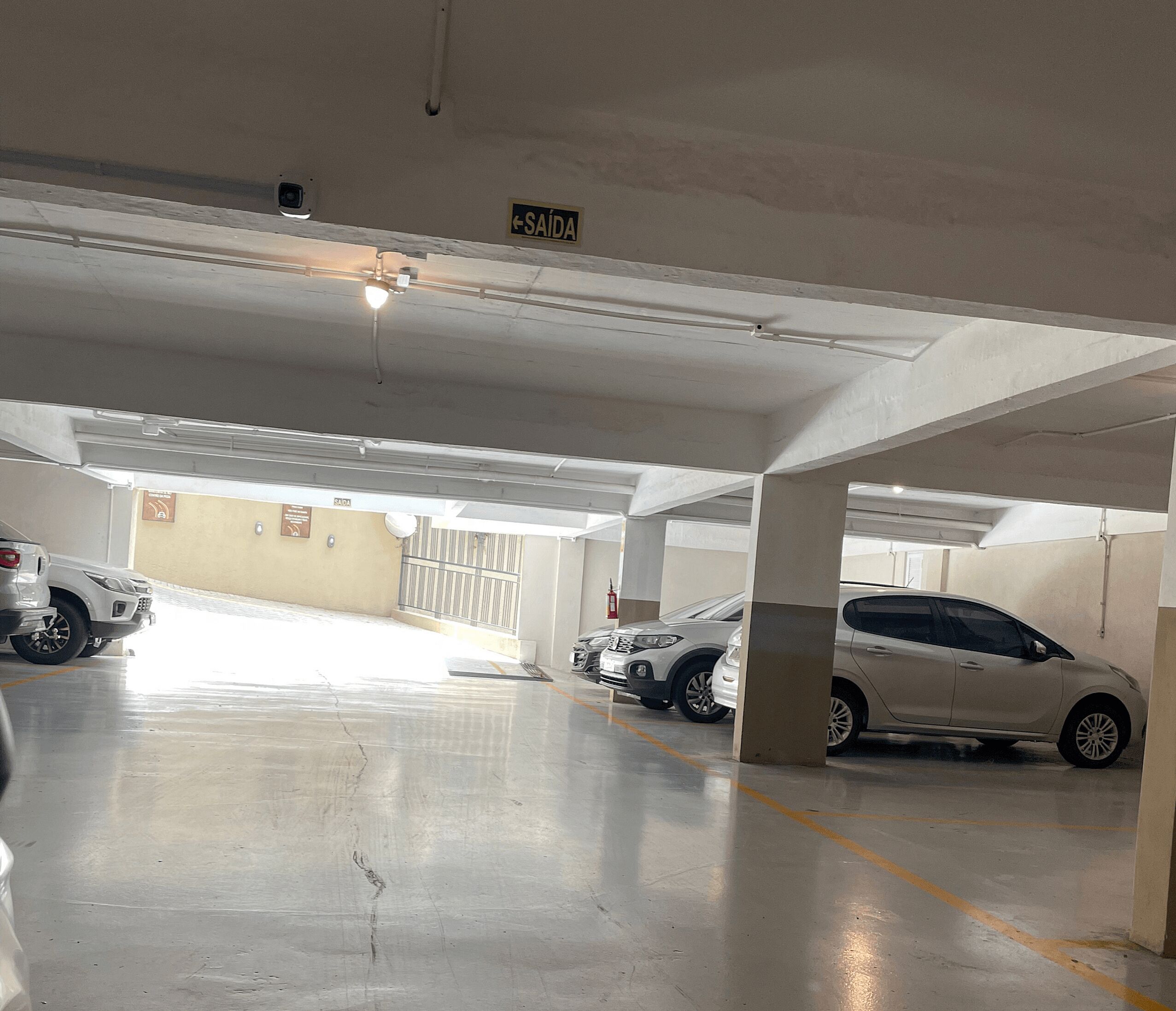 A parking garage with multiple cars parked under a white ceiling.
