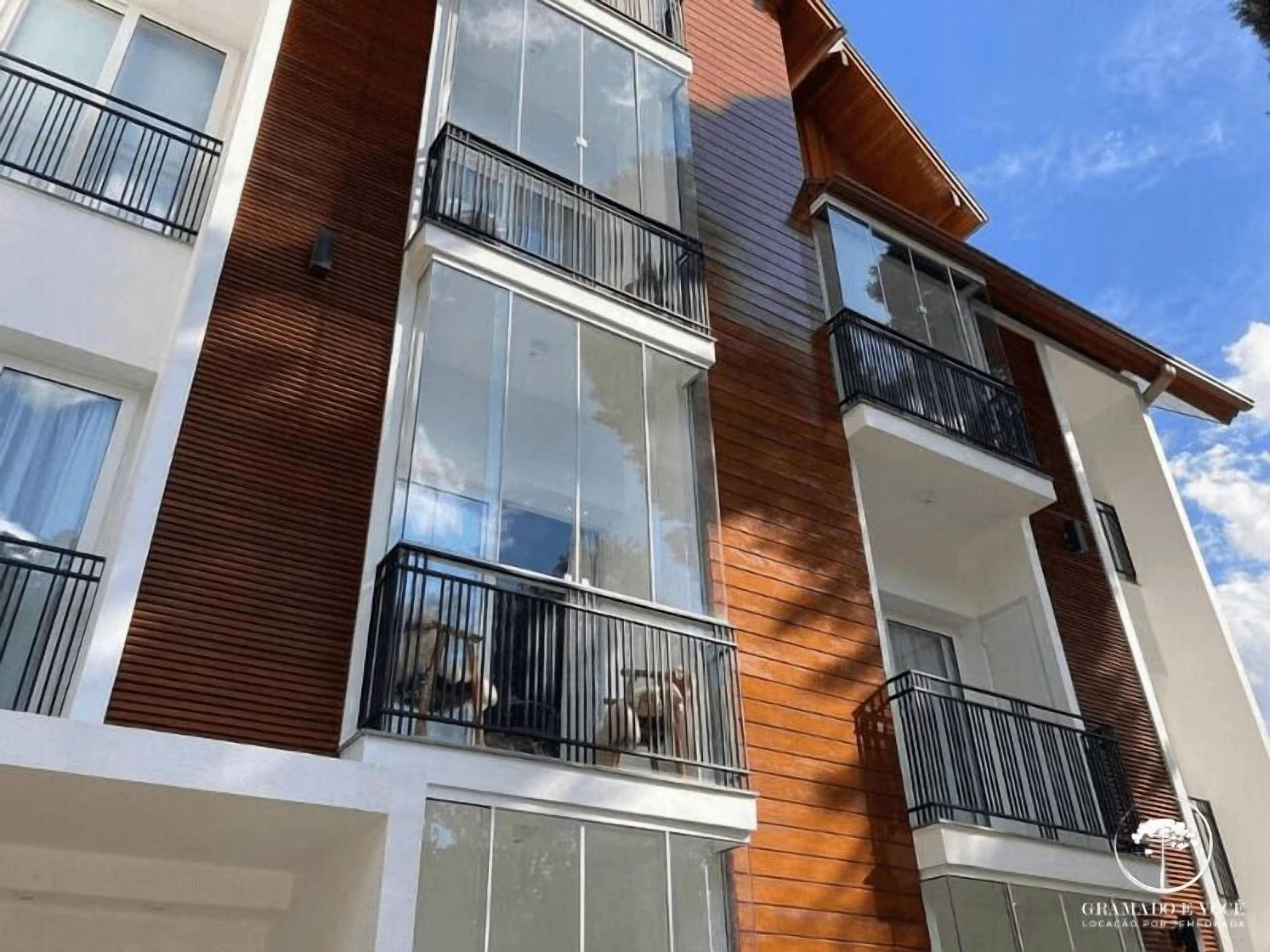 A multi-story building with balconies, large windows, and a mix of wooden and white exterior walls.