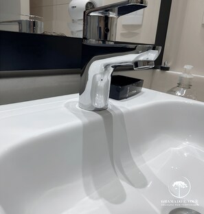 A modern bathroom sink with a chrome faucet and a soap dispenser. - Apartamento Novo Loft One Centro Gramado (Gramado)