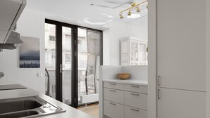 Eine moderne Küche mit großem Fenster, weißen Schränken und einem eingebauten Backofen.