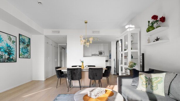 Ein modernes Wohnzimmer mit einer Couch, einem Essbereich mit Stühlen und einer Küche im Hintergrund.