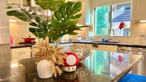 A modern kitchen with a granite countertop, a large green plant, a decorative mushroom, and a red pot on the stove. - Jie’s Choice - Sweet Home in Pasadena.

 (Pasadena)