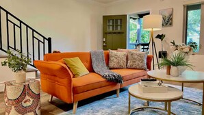 A living room with an orange sofa, a patterned rug, a round coffee table, and a staircase. - Jie’s Choice - Sweet Home in Pasadena.

 (Pasadena)