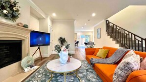 A living room with a fireplace, a television, an orange sofa, and a staircase. - Jie’s Choice - Sweet Home in Pasadena.

 (Pasadena)