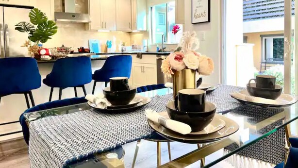 A modern kitchen with white cabinets, a dining area with blue chairs, and a glass table set for two. - Jie’s Choice - Sweet Home in Pasadena.

 (Pasadena)