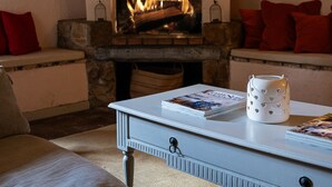 A cozy living room with a fireplace, a sofa, and a coffee table with magazines.
