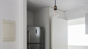 Una cocina moderna con un refrigerador de acero inoxidable, una planta en maceta y un inodoro blanco.