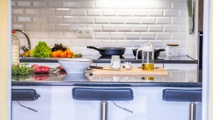 Una cocina moderna con azulejos blancos tipo metro, encimera negra y tabla de cortar de madera.