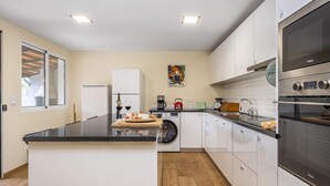 Una cocina moderna con una isla central, electrodomésticos integrados y un ventanal grande.