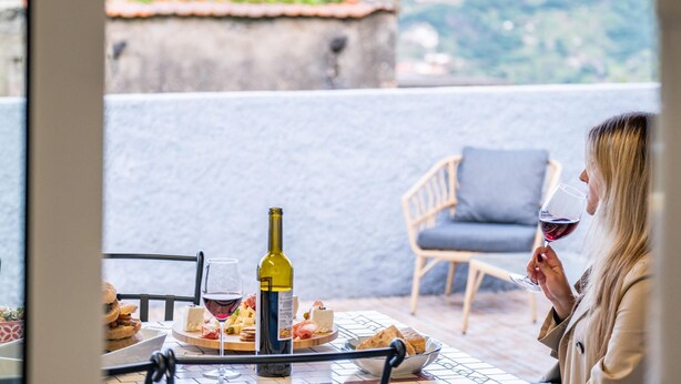 Una terraza con una mesa lista para una comida, una botella de vino y una copa de vino.