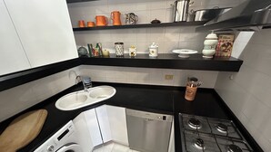 Une cuisine de taille réduite équipée d’un lave-vaisselle, d’une cuisinière et d’un évier.