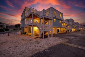 A beachfront property with multiple levels, outdoor seating, and a staircase leading to the entrance.