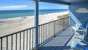 A beach view from a covered balcony with a railing, a small table, and two chairs. - Luxury Gulf-Front Condo w/ Balcony Views | 3BR/2BA | Pool | Beach Access | Sleeps 6 | Great Sunsets | Anna Maria Island (Holmes Beach)