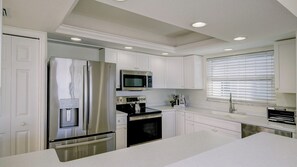 A modern kitchen with white cabinetry, stainless steel appliances, and a built-in water dispenser. - Luxury Gulf-Front Condo w/ Balcony Views | 3BR/2BA | Pool | Beach Access | Sleeps 6 | Great Sunsets | Anna Maria Island (Holmes Beach)