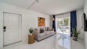 A spacious living room with a sofa, a painting, and a balcony with a view. - Wynwood Charm 1, Live the art.1 Free Gated Parking (Miami)