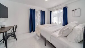 A bedroom with a bed, a desk, and a chair. There are curtains on the windows. - Wynwood Charm 1, Live the art.1 Free Gated Parking (Miami)