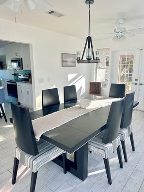 Een moderne eetruimte met een donker houten tafel, zes stoelen en een kroonluchter.