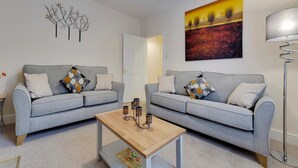 A modern living room with two grey sofas, a wooden coffee table, and a floor lamp. - Pass the Keys | Modern and Spacious Terrace in Central Cambridge (Cambridge)