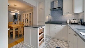 Una cocina moderna con armarios blancos, una isla integrada y piso estampado.