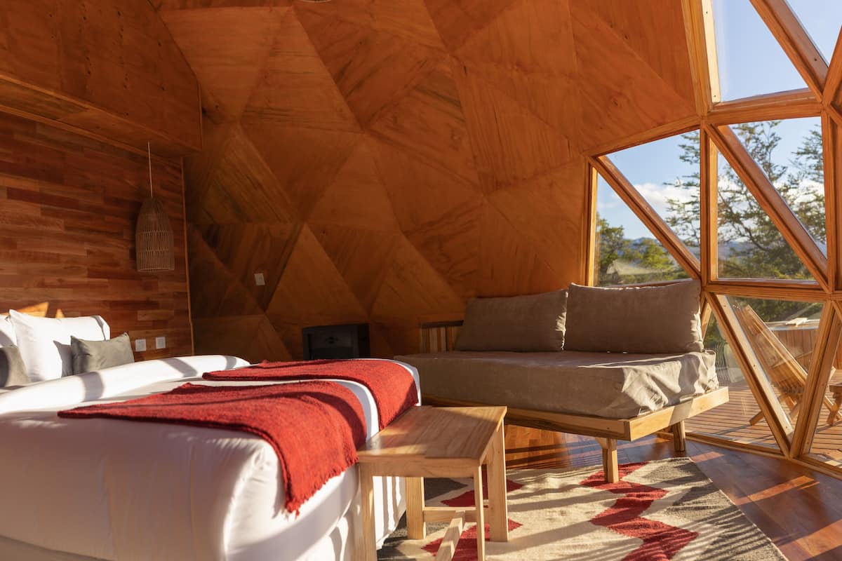 A cozy interior with a bed, a sofa, and a dining table, all made of wood.
