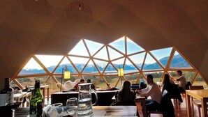 A dining area with a view of mountains through a geometric window structure.