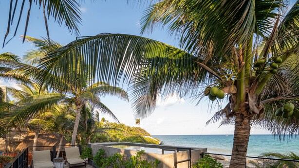 A beachside lounge with a concrete floor, lounge chairs, and a railing overlooking the ocean. - Tropicalito Tulum (Tulum)