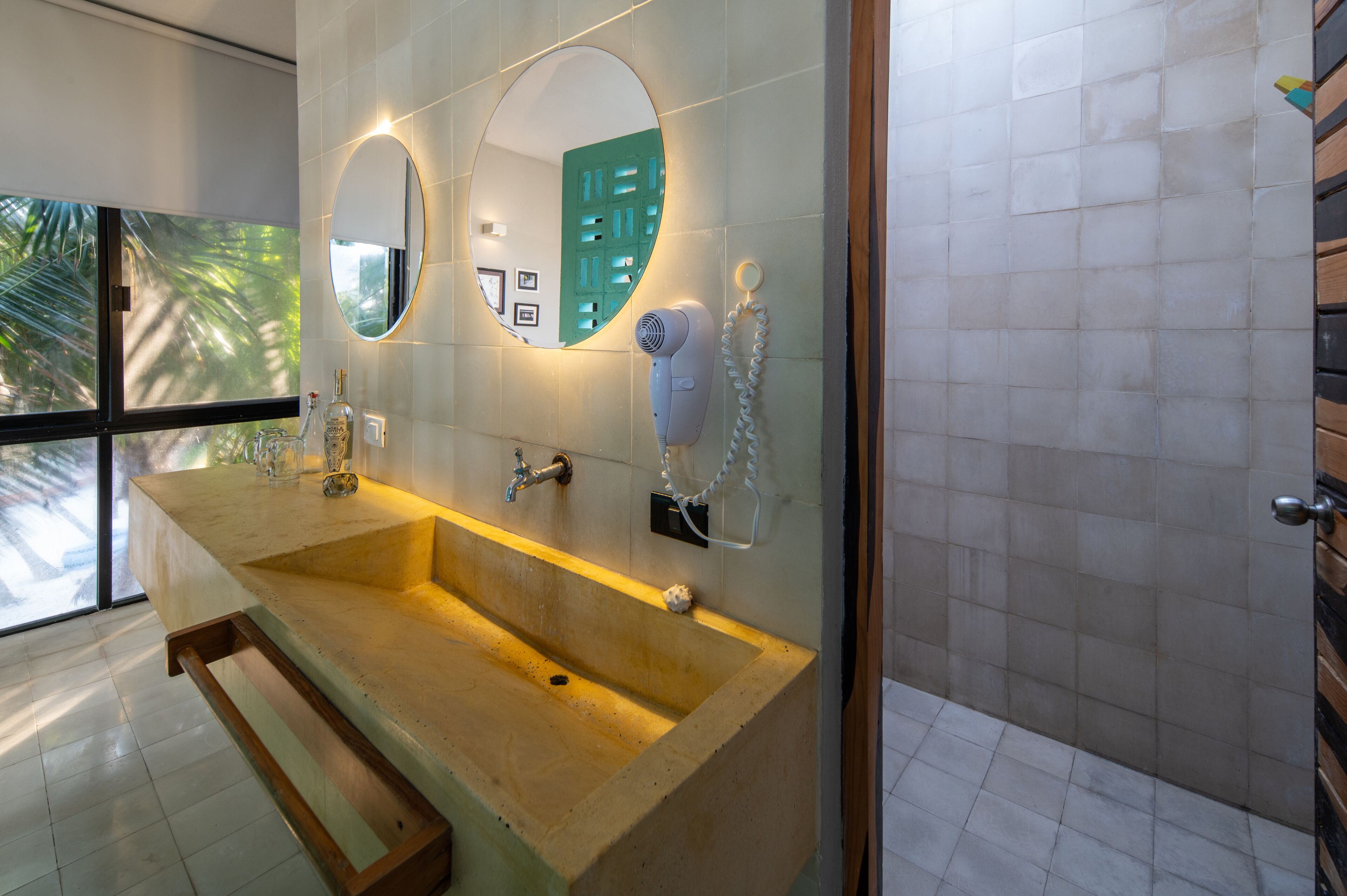 A bathroom with a large sink, two mirrors, a hairdryer, and a towel rack.