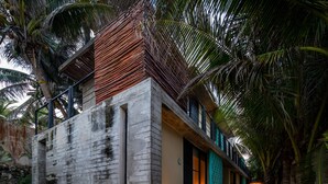 A modern building with a concrete facade, a wooden deck, and a pathway leading to the entrance. - Tropicalito Tulum (Tulum)