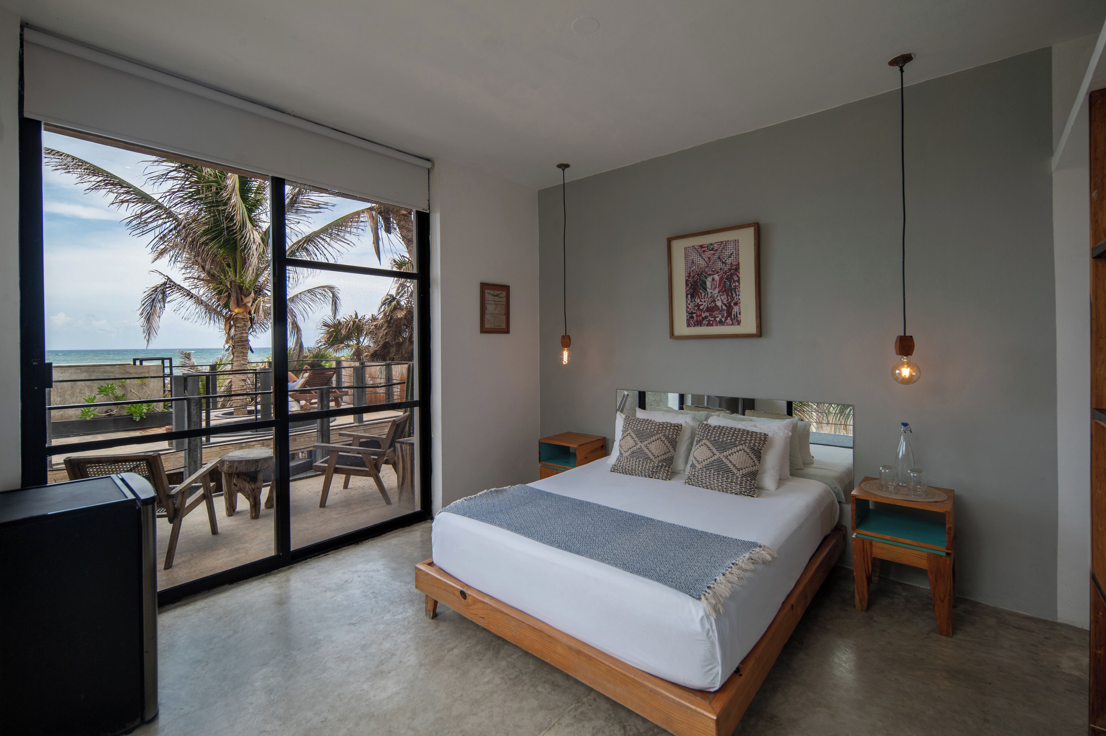 A bedroom with a large bed, a view of the ocean, and a balcony with chairs and a table.