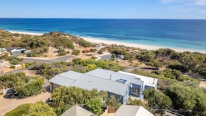 A coastal property with a large house, a driveway, and a beach in the background.