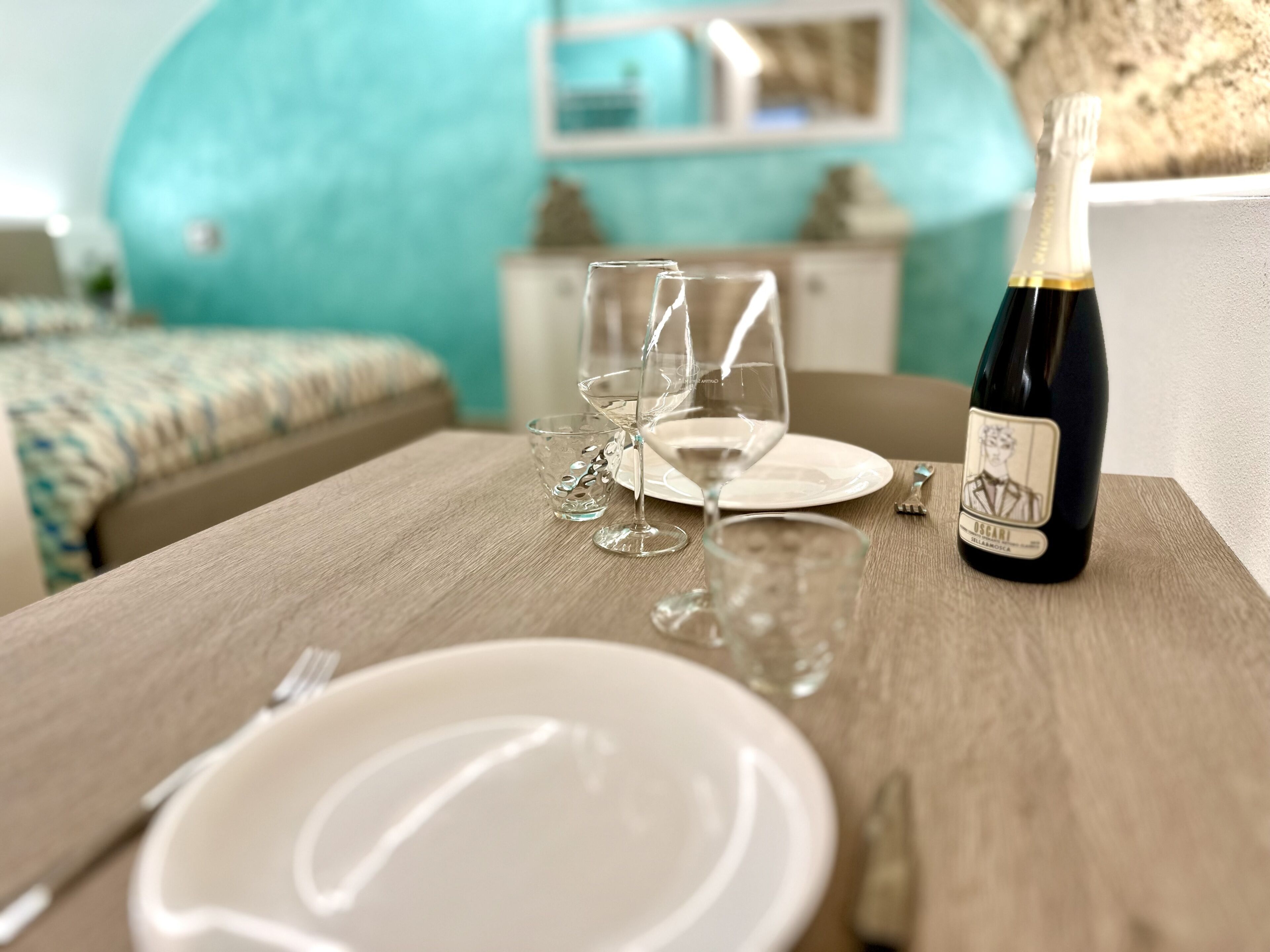 A dining table with a bottle of wine, glasses, and cutlery.