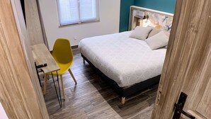 Ein Schlafzimmer mit Bett, Schreibtisch, Stuhl und Fenster.