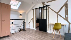 Ein modernes Interieur mit Holzboden, einem gelben Sessel, einem Schreibtisch und einem Fernseher.