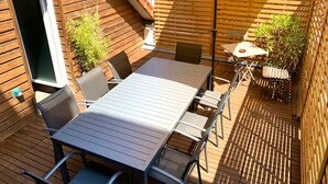 Eine Terrasse im Freien mit Tisch, Stühlen, einem gelben Sonnenschirm und Holzzaun.
