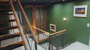 Una scala con gradini in legno e ringhiere in metallo, che conduce a una stanza con pareti verdi e un quadro incorniciato.