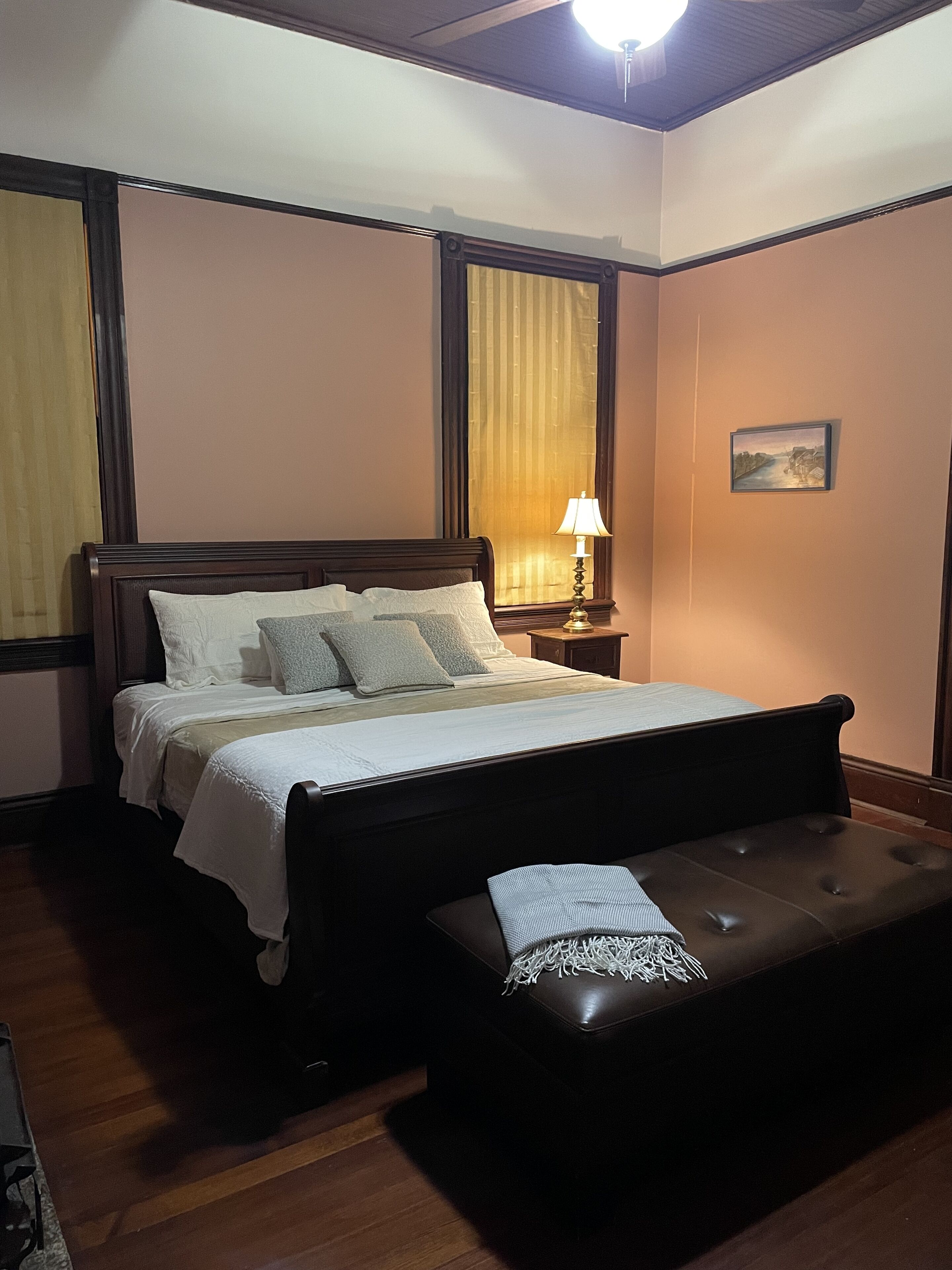 Quarto bem organizado com cama, abajur e um banquinho.