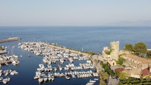 A marina with numerous boats docked, a historic tower, and a coastal building with a red roof. - Gorgeous Villa with outbuilding for a relaxing vacation (Torre Colonna-Sperone)