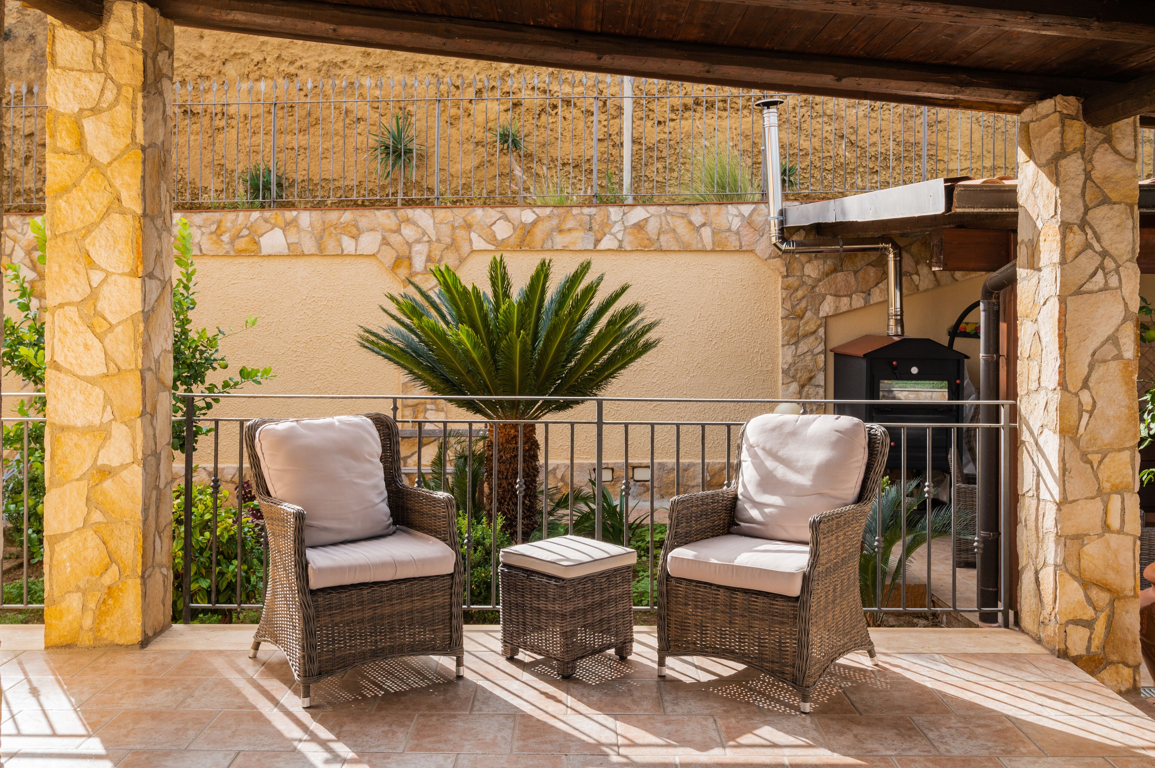 A patio with wicker furniture and a stone wall.