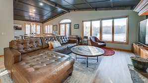 A spacious living room with a large sectional sofa, a round coffee table, and a television. - Lake Arbutus Retreat w/ Hot Tub & Game Room (Neillsville)