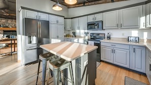 A modern kitchen with stainless steel appliances, white cabinetry, and a central island. - Lake Arbutus Retreat w/ Hot Tub & Game Room (Neillsville)