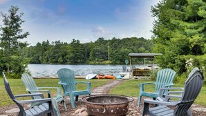 A lakeside seating area with Adirondack chairs and a fire pit. - Lake Arbutus Retreat w/ Hot Tub & Game Room (Neillsville)