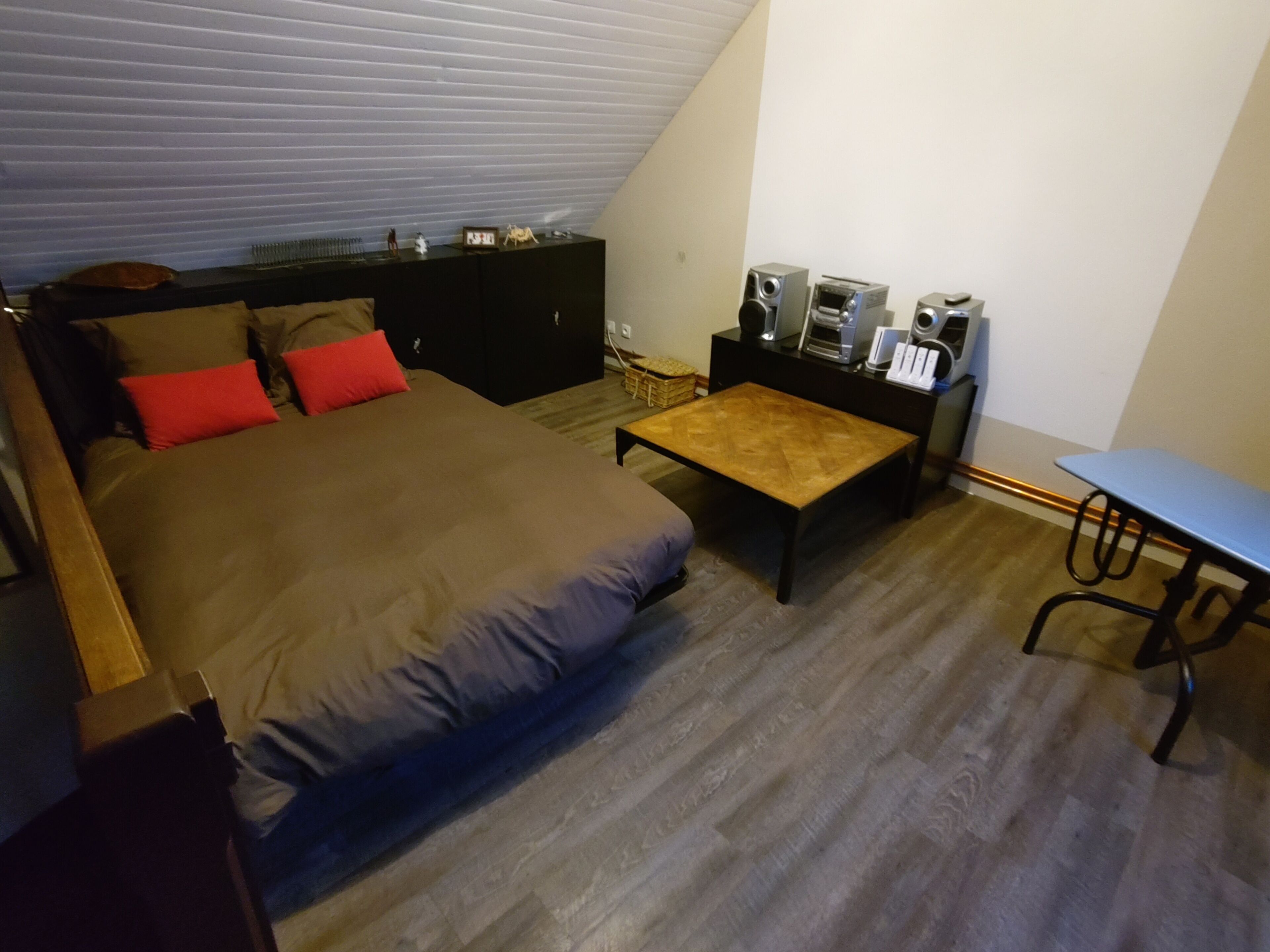 Ein Schlafzimmer mit einem Bett, einem Holztisch, einem Schreibtisch und einer Lautsprecheranlage.