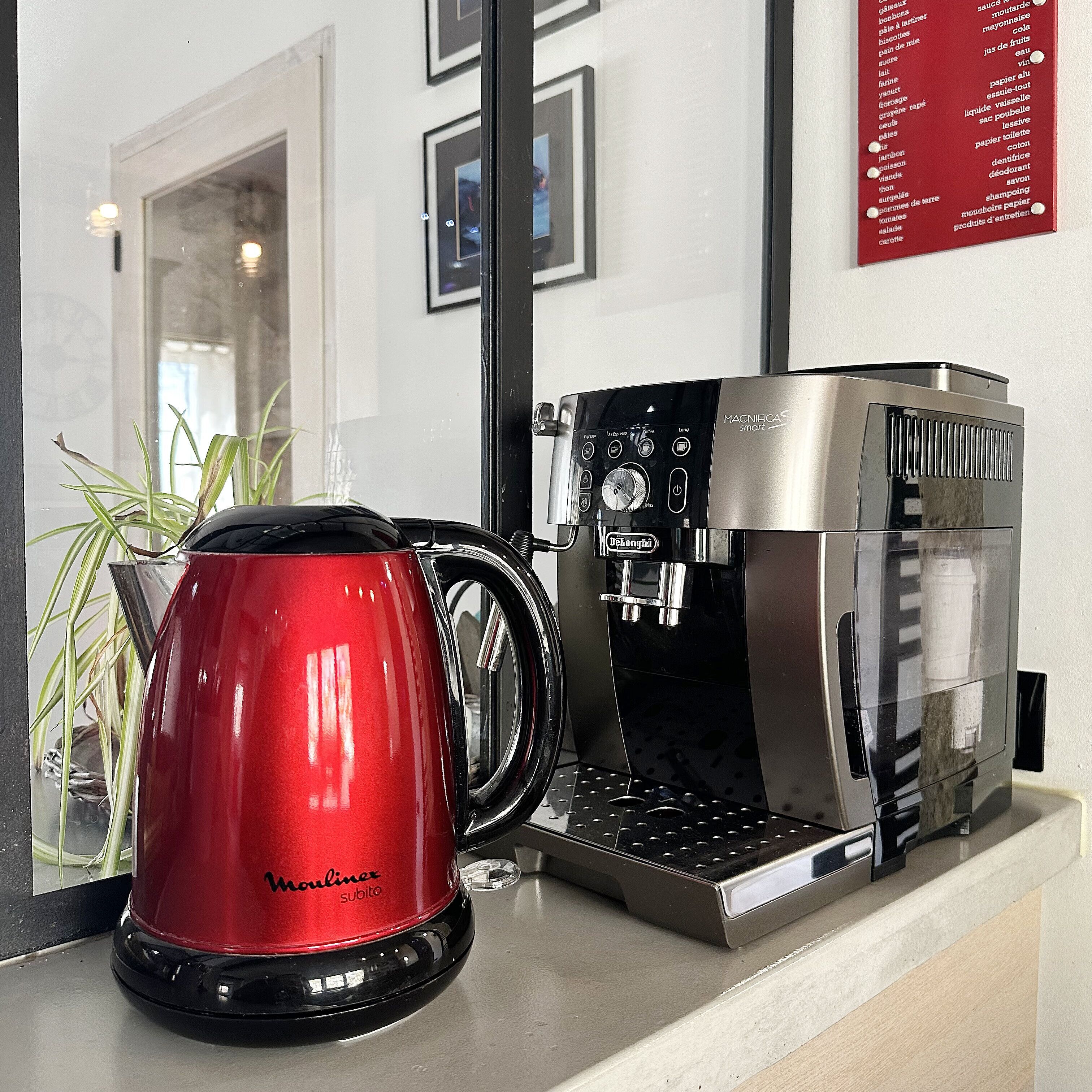 Une machine à café et une bouilloire rouge sont posées sur un plan de travail.