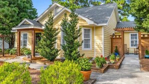 Une maison à deux étages dotée d’un porche abrité et d’un petit jardin.