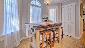 Une cuisine avec un îlot central en bois, deux tabourets de bar et un luminaire suspendu.